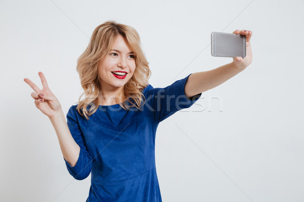 Young lady make selfie with peace gesture by phone Stock photo © deandrobot