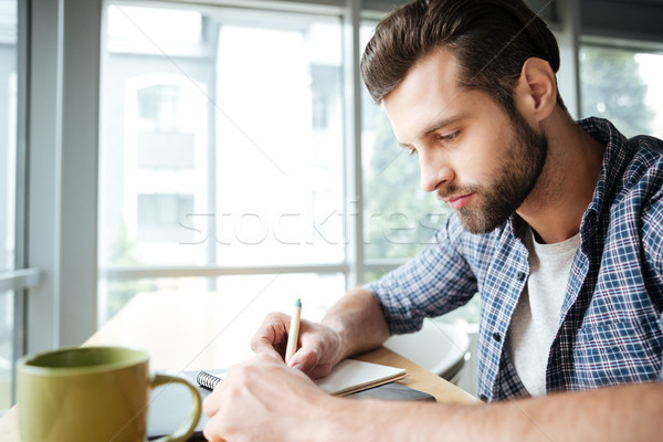 Handsome man in office coworking while writing notes Stock photo © deandrobot