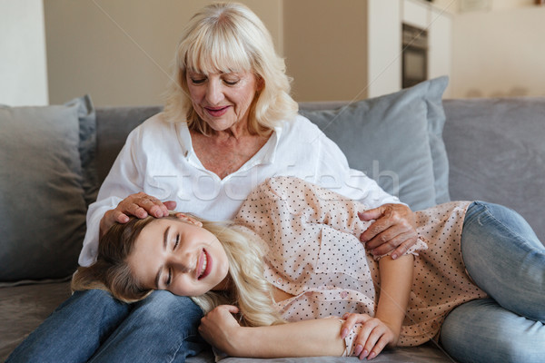 Smiling young lady lies on sofa at home with grandmother Stock photo © deandrobot