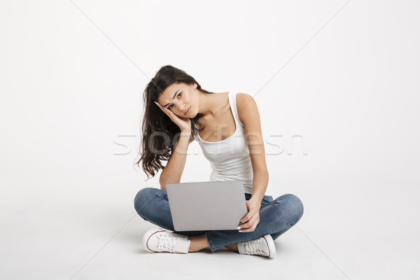 Portrait of an upset girl dressed in tank-top holding laptop Stock photo © deandrobot