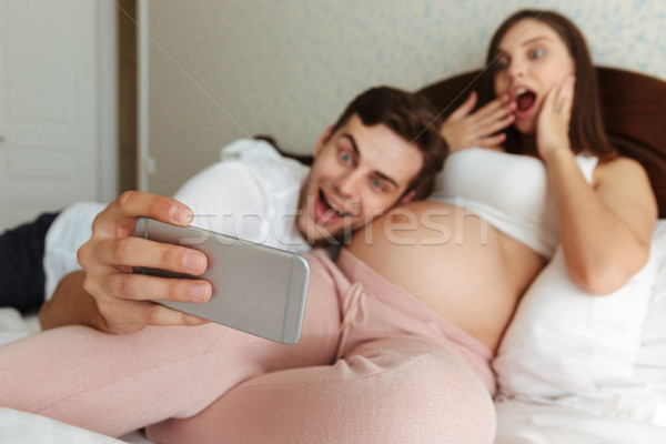 Excited young pregnant couple taking selfie Stock photo © deandrobot