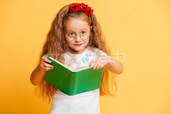Cute pretty girl wearing glasses looking aside reading book. Stock photo © deandrobot