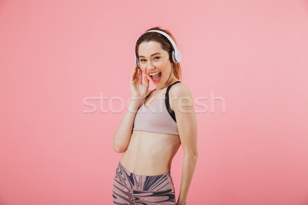 Cheerful sportswoman in headphones listening music and looking at camera Stock photo © deandrobot