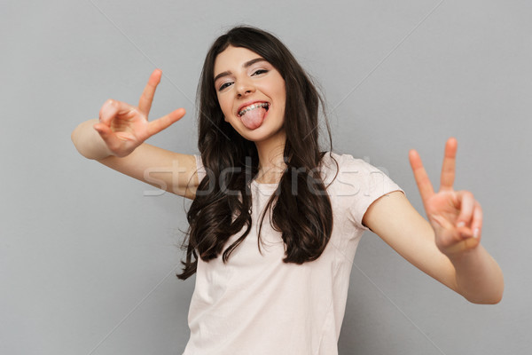 Pretty cute young lady showing peace gesture. Stock photo © deandrobot