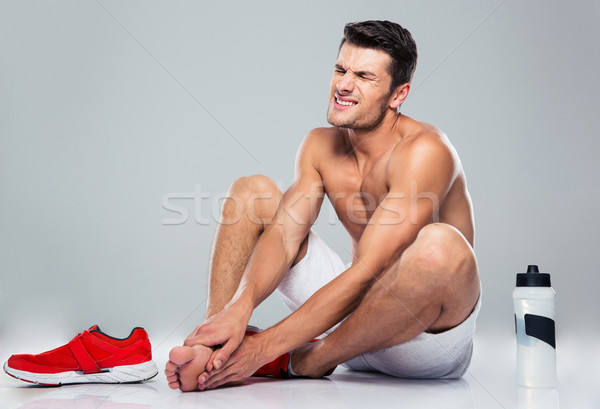 Portrait of a fitness man with foot pain Stock photo © deandrobot
