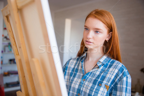Concentraited attractive female artist painting on canvas in art workshop Stock photo © deandrobot