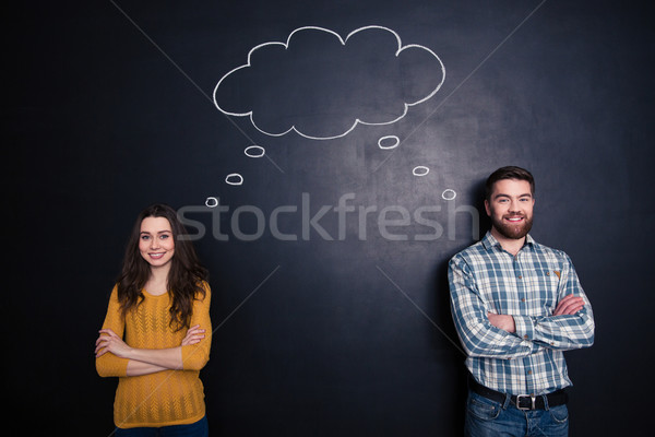 Happy couple having the same thoughts over black board background Stock photo © deandrobot