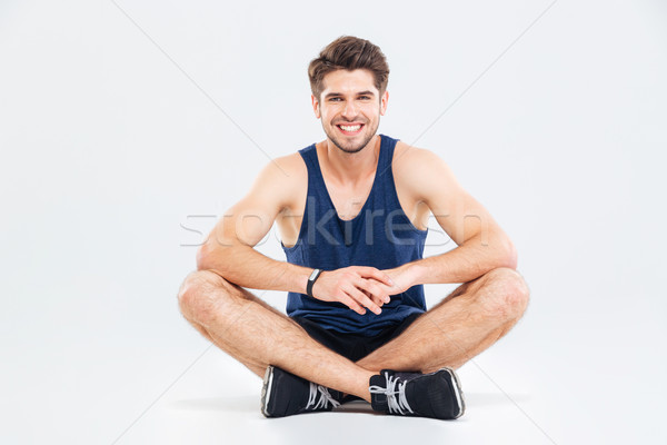 Jeune homme athlète séance jambes croisées blanche [[stock_photo]] © deandrobot