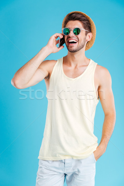 Wesoły młody człowiek stałego mówić komórka hat Zdjęcia stock © deandrobot