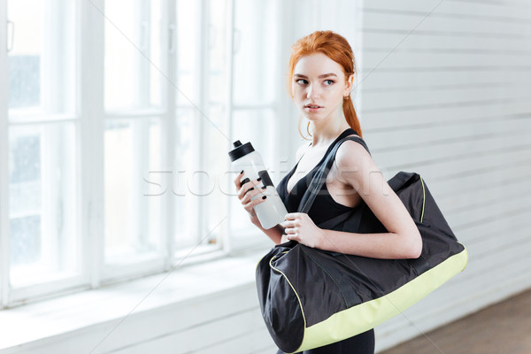 Young woman with bottle of water and sports bag Stock photo © deandrobot