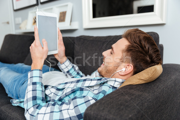 Happy bristle man using tablet computer while listening music Stock photo © deandrobot