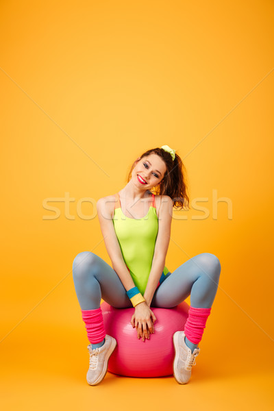 Attractive young fitness woman posing over yellow background. Stock photo © deandrobot