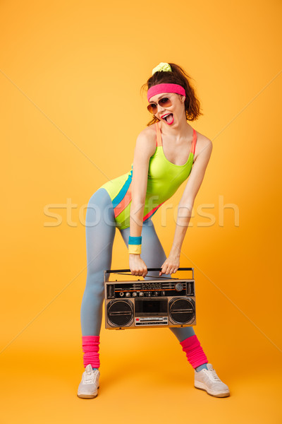 Happy beautiful young fitness woman standing and holding retro boombox Stock photo © deandrobot