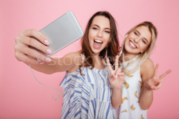 Two happy young women listening to music and talking selfie Stock photo © deandrobot