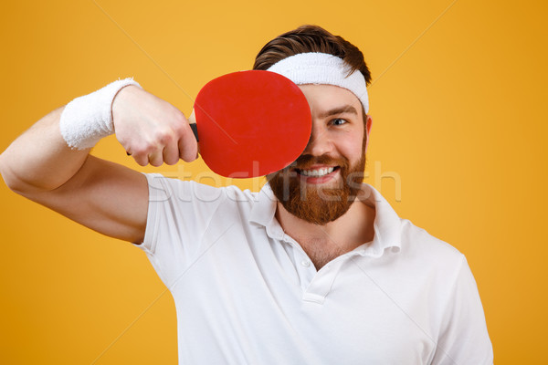Cheerful young sportsman holding racket for table tennis. Stock photo © deandrobot