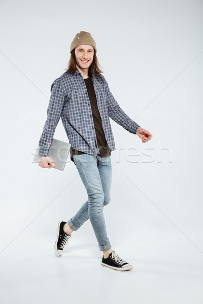 Vertical image of Smiling Hipster walking with laptop Stock photo © deandrobot