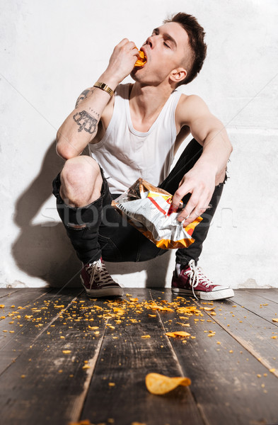 çekici genç oturma yeme cips beyaz Stok fotoğraf © deandrobot