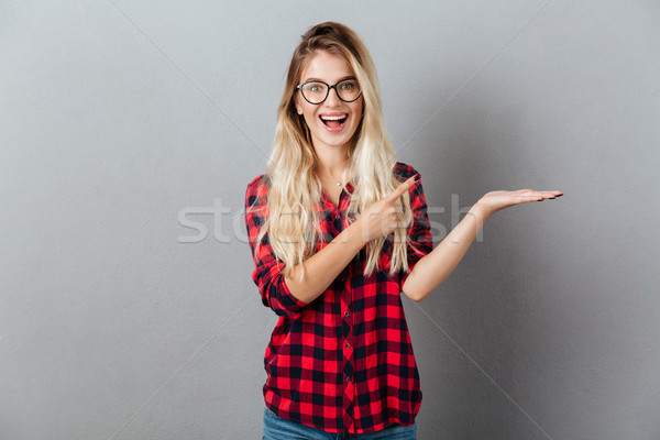 Emotional smiling young blonde woman holding copyspace Stock photo © deandrobot