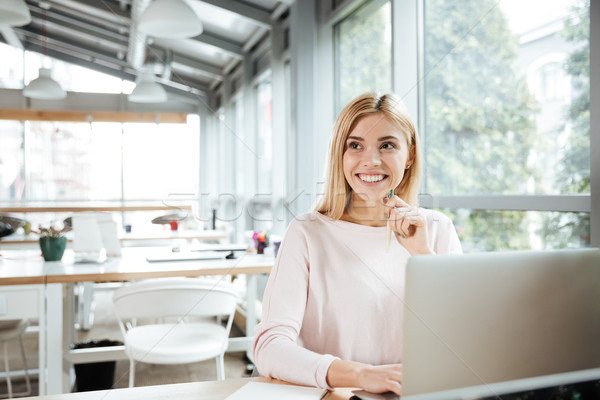 Cheerful lady sitting in office coworking while using laptop Stock photo © deandrobot