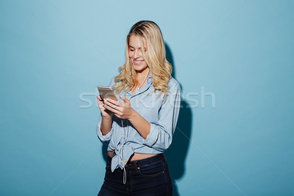 Cheerful young pretty blonde woman listening music with earphones. Stock photo © deandrobot