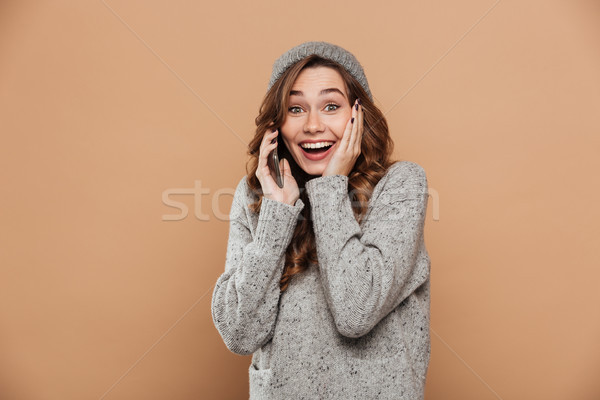 Young smiling pretty girl in gray hat and sweater keeping hand o Stock photo © deandrobot