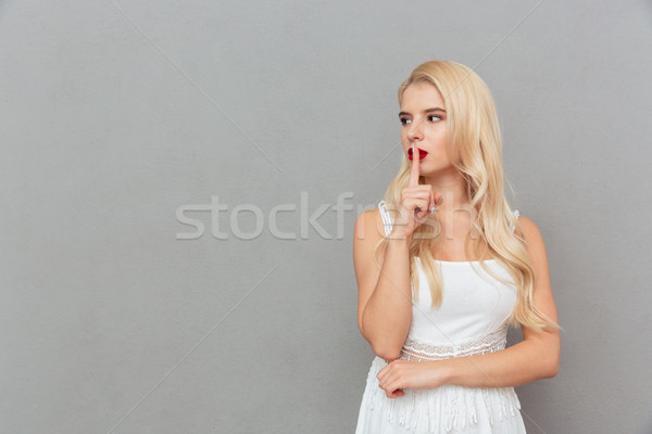 Portré fiatal lány mutat csend kézmozdulat másfelé néz Stock fotó © deandrobot