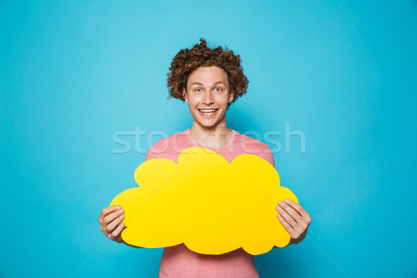 Photo of optimistic smiling man 20s with brown curly hair holdin Stock photo © deandrobot