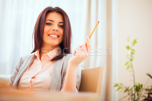 Portrait of a young beautiful confident woman in casual business cloths holding a pencil Stock photo © deandrobot