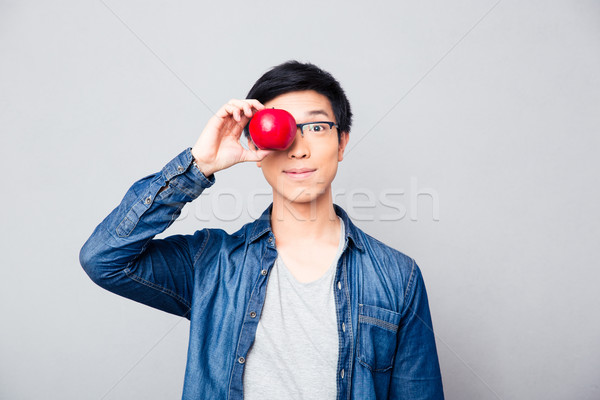 Stock photo: Young asian man covering his eyes with apple