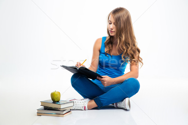 Girl sitting at the floor and writing notes Stock photo © deandrobot