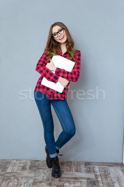 Cheerful girl in glasses posing and smiling hugging laptop Stock photo © deandrobot