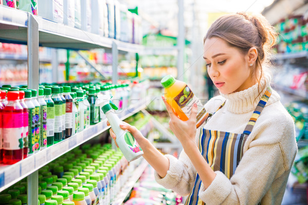 Concentrated woman choosing agricultural chemicals for flowers and plants  Stock photo © deandrobot