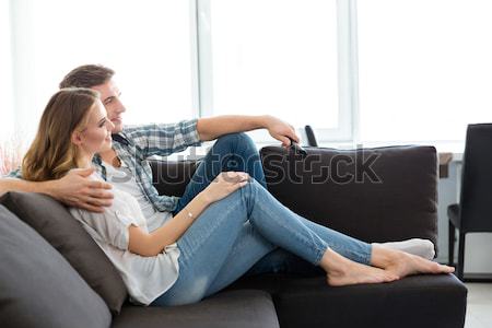Happy couple sitting on sofa and watching TV  Stock photo © deandrobot