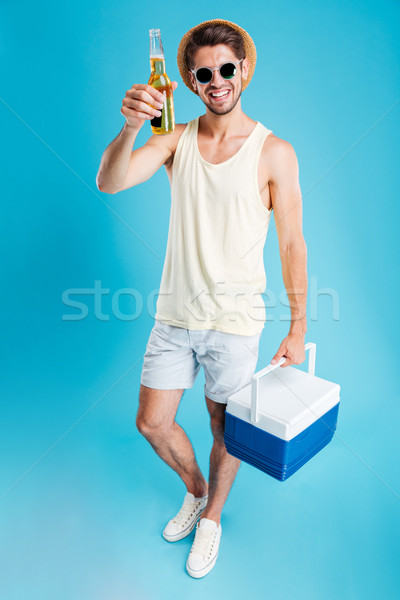 Smiling young man holding cooler bag and drinking beer Stock photo © deandrobot