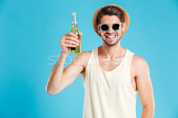 Happy man in hat and sunglasses holding bottle of beer Stock photo © deandrobot
