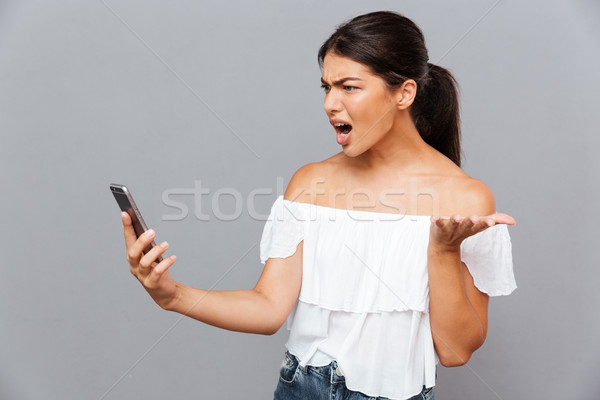 Böse Frau Smartphone isoliert grau Stock foto © deandrobot