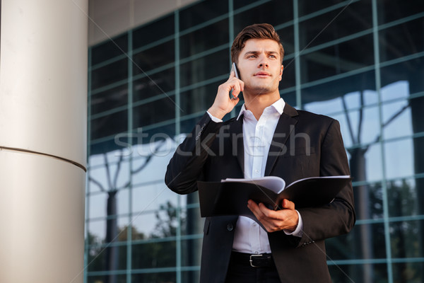 Stock photo: Businessman in suit holding folders and talking on the phone