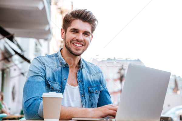 Foto d'archivio: Sorridere · casuale · uomo · utilizzando · il · computer · portatile · seduta · cafe