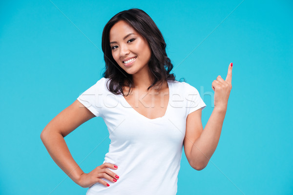 Cheerful young vietnamese girl pointing finger up at copyspace Stock photo © deandrobot