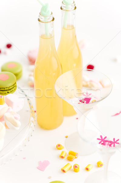 Two glasses and bottle of lemonade on table with sweets Stock photo © deandrobot