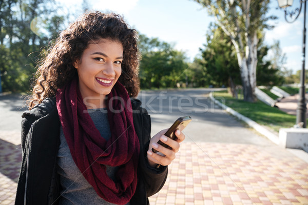 Attractive dark-skinned lady chatting and looking at camera Stock photo © deandrobot
