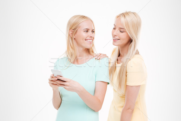 Young attractive lady showing her phone to the friend Stock photo © deandrobot