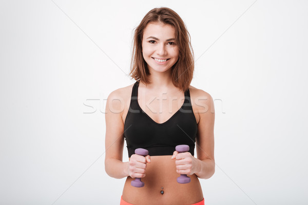 Smiling young fitness lady make exercises with dumbbells Stock photo © deandrobot