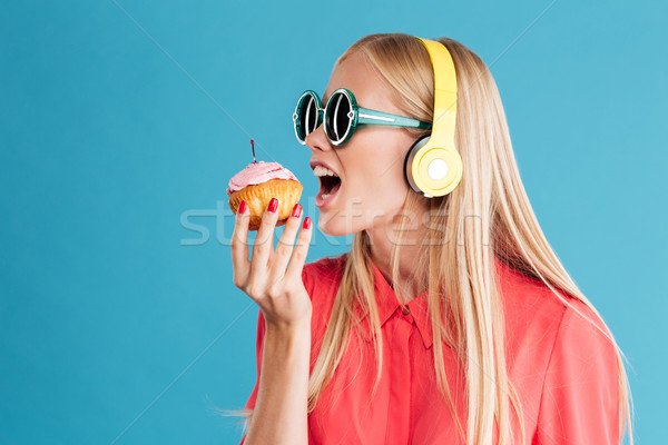 Nő napszemüveg harap minitorta hallgat zene Stock fotó © deandrobot