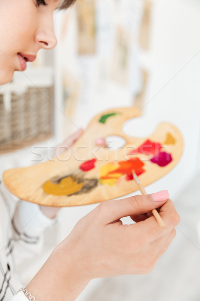 Female artist holding palette and mixing paint colors in studio Stock photo © deandrobot