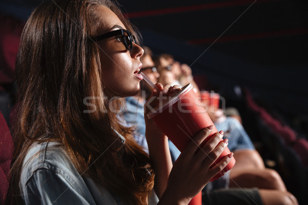 Lady sitting in cinema watch film drinking aerated sweet water. Stock photo © deandrobot