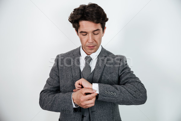 Successful businessman in suit standing and buttoning cuff sleeves Stock photo © deandrobot
