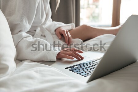 [[stock_photo]]: Image · femme · peignoir · lit · utilisant · un · ordinateur · portable · chambre · d'hôtel
