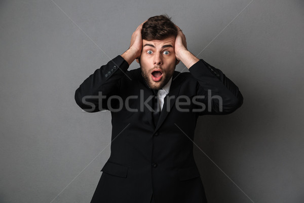 Close-up portrait of shocked young businessman holding his head, Stock photo © deandrobot