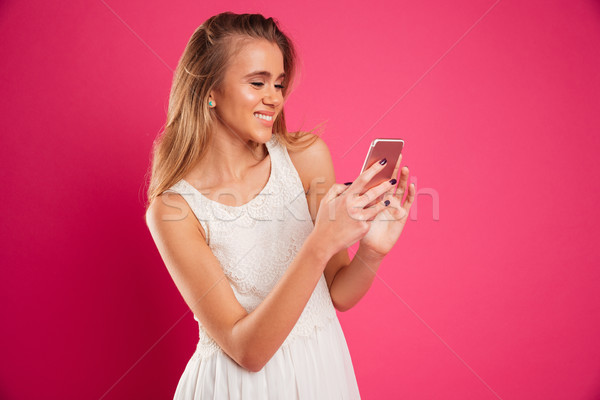 Portrait of a smiling nice girl in dress texting Stock photo © deandrobot